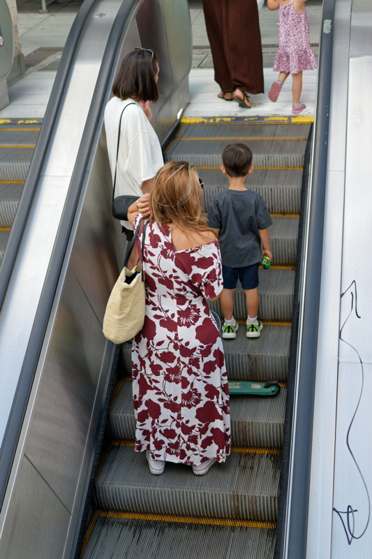 18 - Person wearing a white and maroon floral maxi dress while riding an escalator
